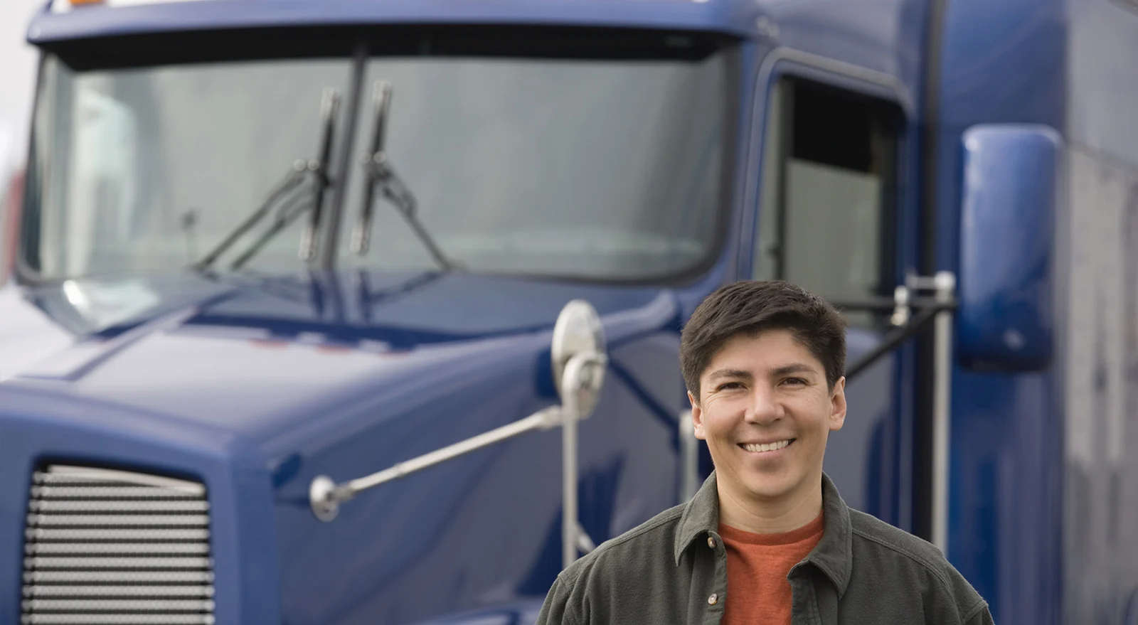 Driver standing in front of a blue semi truck
